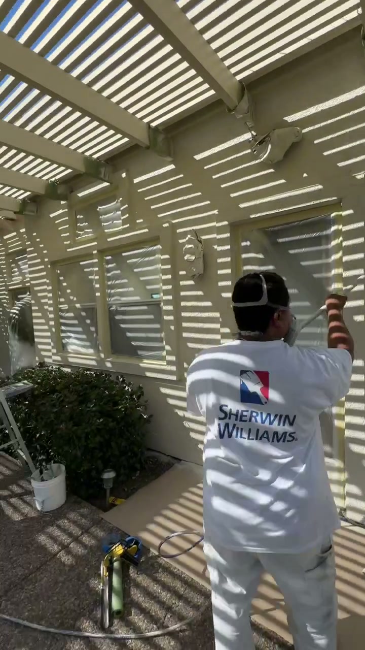 Bronco painter spraying window trim on a masked exterior